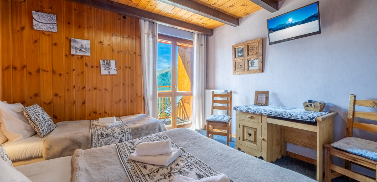 Chambre avec lits jumeaux, serviettes pliées sur les couvre-lits et télévision murale