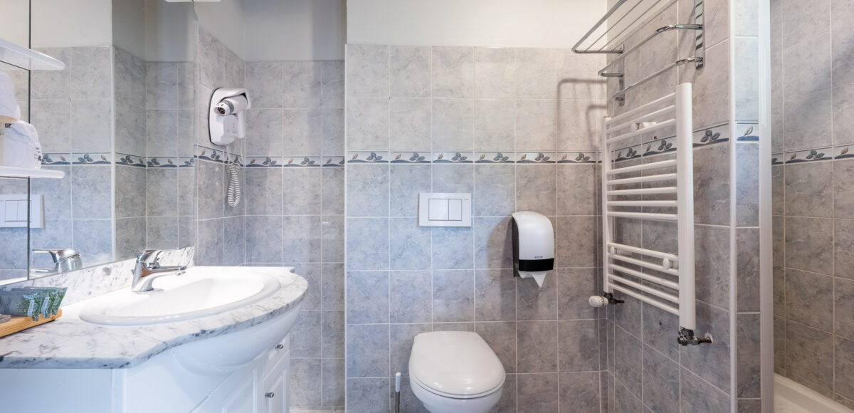 Salle de bain avec vasque en marbre, sèche-cheveux et sèche-serviettes chauffant blanc