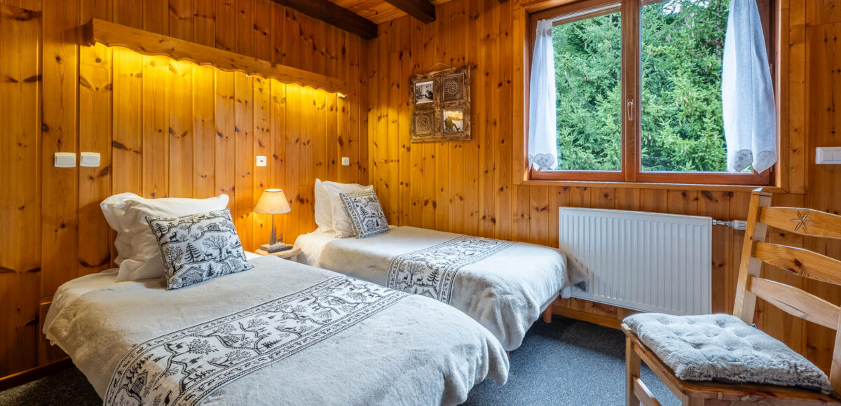 Chambre Familiale Confort avec deux lits jumeaux à motifs de cerfs face aux sapins