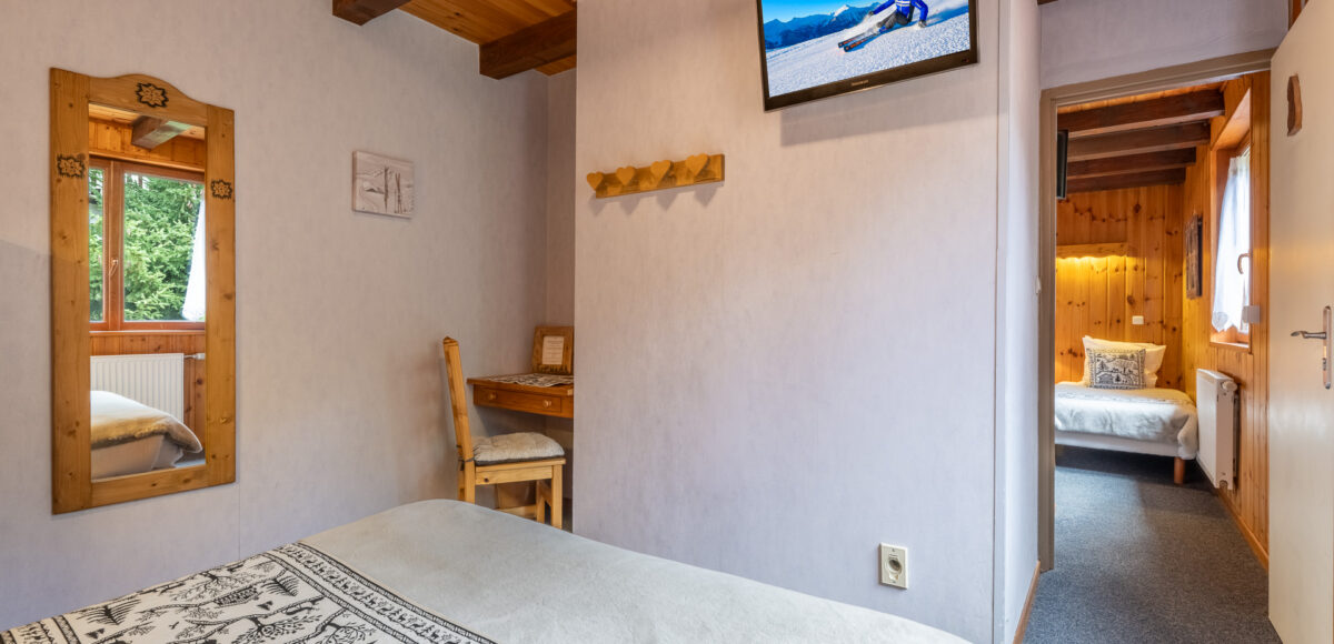 Enfilade de deux chambres communicantes avec miroir, bureau et téléviseur mural