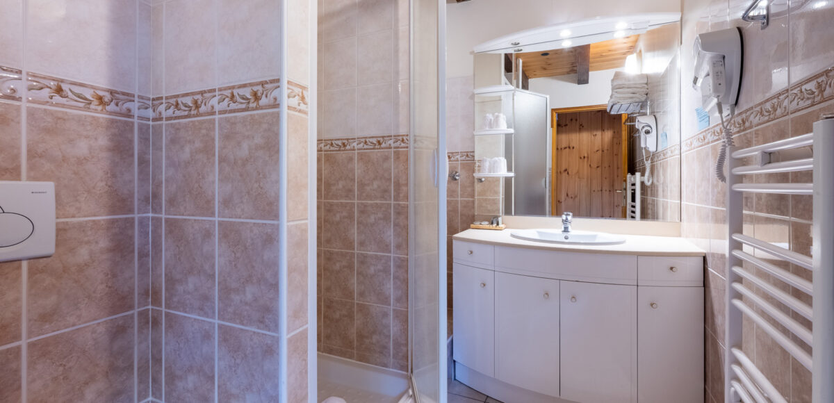 Salle de bain avec vasque blanche, douche vitrée et sèche-serviettes chauffant