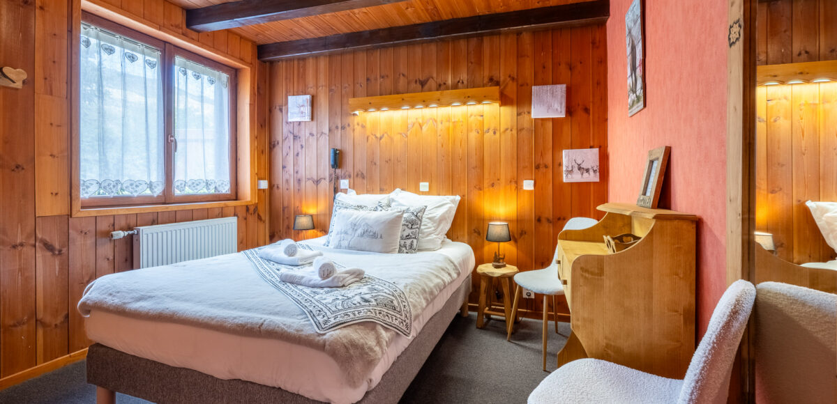 Lit double avec bureau en bois, chaise et miroir dans un coin chaleureux