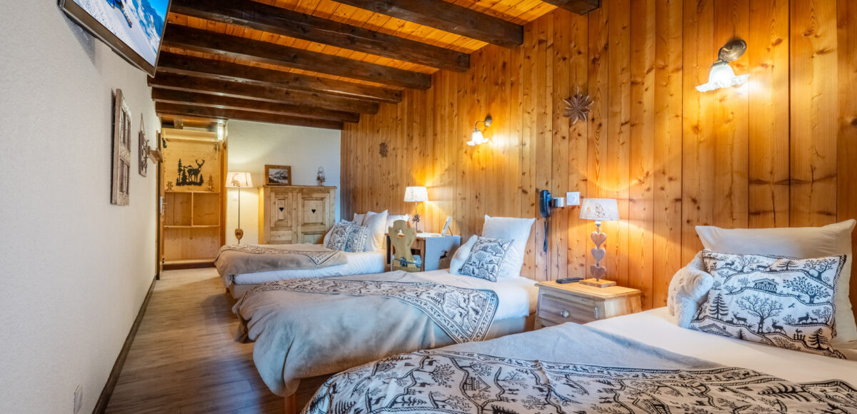 Rangée de trois lits jumeaux avec plaids à motifs de cerfs sous poutres en bois