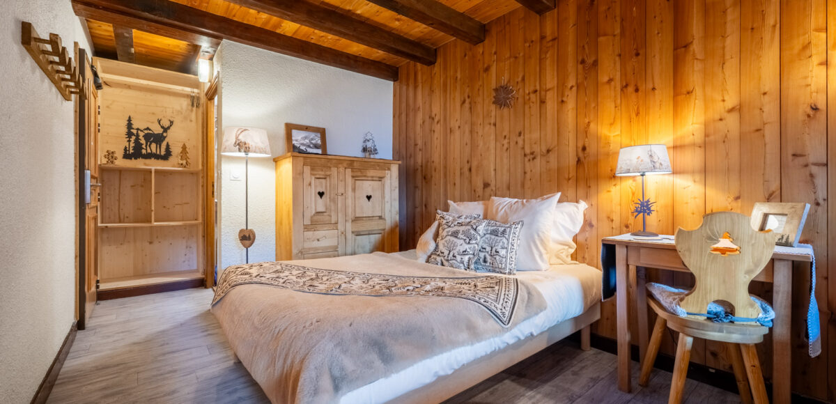 Lit double avec armoire en bois sculpté et lampe chevet dans une chambre chalet