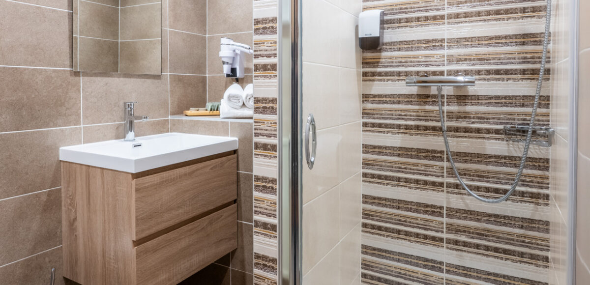 Salle de bain avec douche à l'italienne, vasque en bois et carrelage rayé beige et marron
