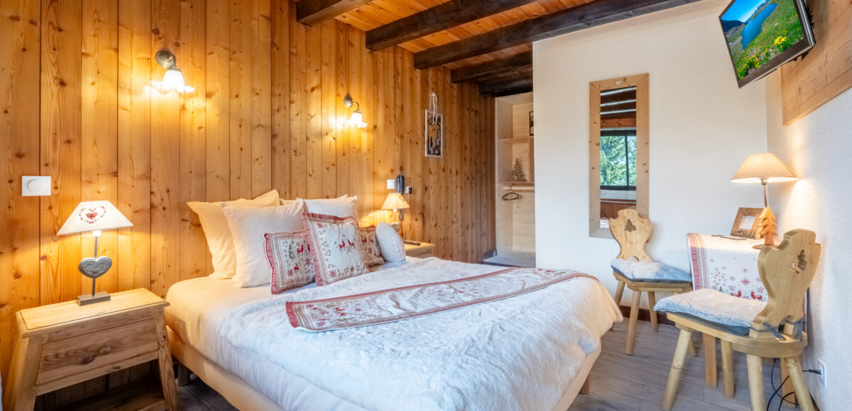 Chambre en bois avec lit double, chaises paysannes et téléviseur mural