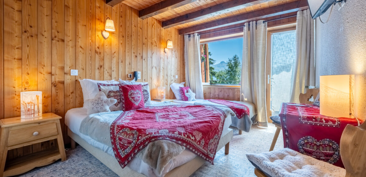 Lit double avec plaid rouge brodé, vue sur la montagne depuis la fenêtre