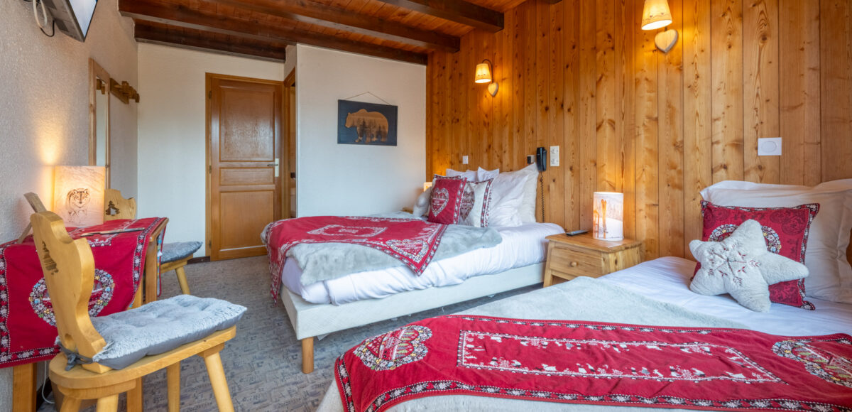 Deux lits jumeaux avec plaids rouges brodés et tableau d'ours au mur