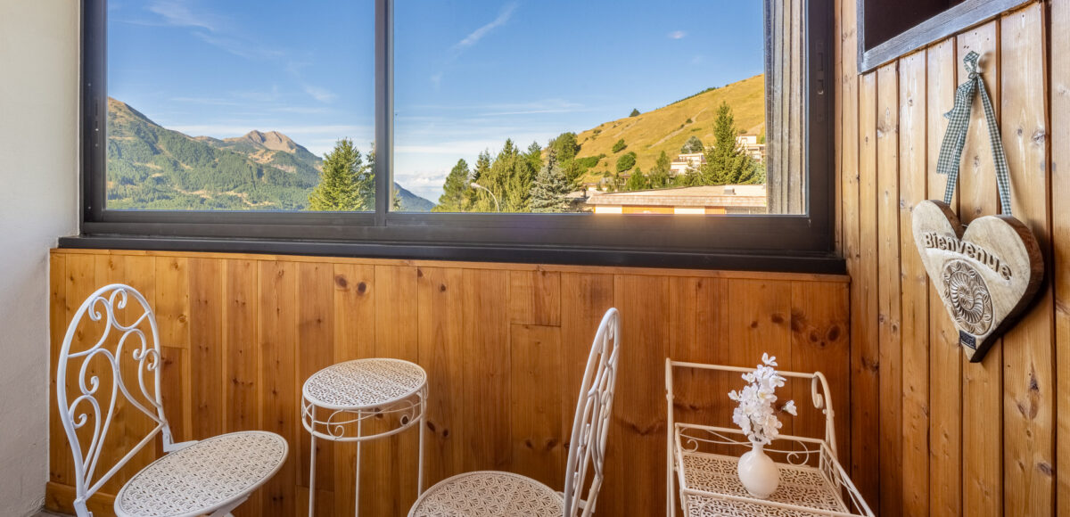 Balcon avec chaises en fer forgé blanc et vue sur les montagnes et la vallée