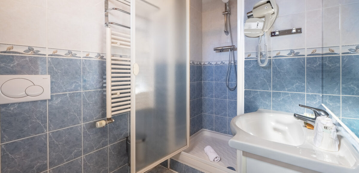 Miroir mural en bois reflétant le lit et la fenêtre de la chambre